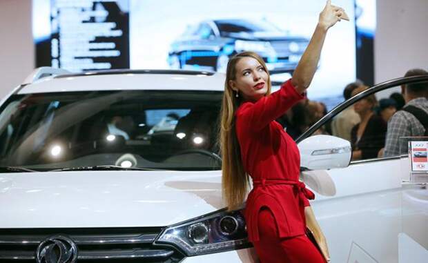 На фото: девушка делает селфи у автомобиля Dongfeng AX7