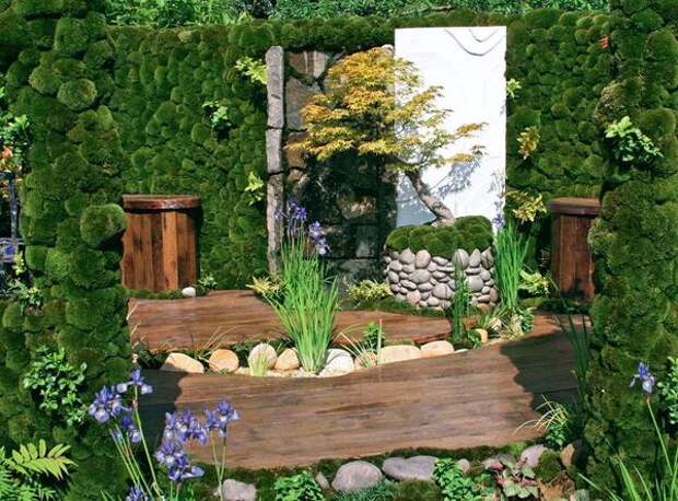 Бонсай, спрятанный в кадушку, декорированную галькой, - словно миниатюра в садовом интерьере.