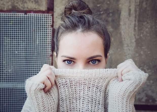 девушка закрывает лицо свитером