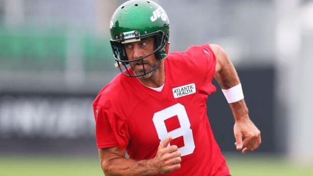 aaron rodgers running in a red training camp jersey