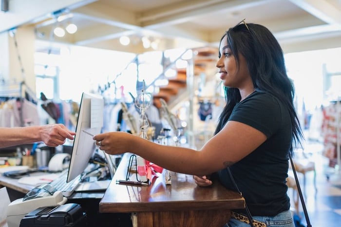 Young woman paying cashier with credit card in a clothing store