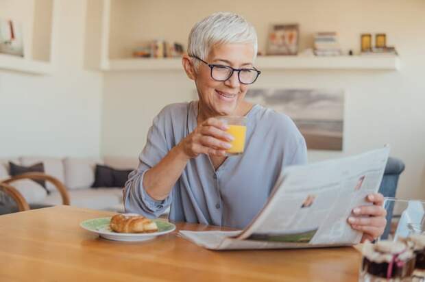 A person at a table reading a newspaper.