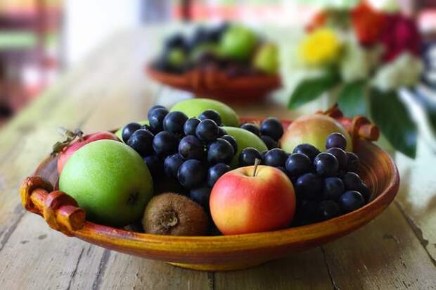 A wooden bowl full of a fruit on a counter.