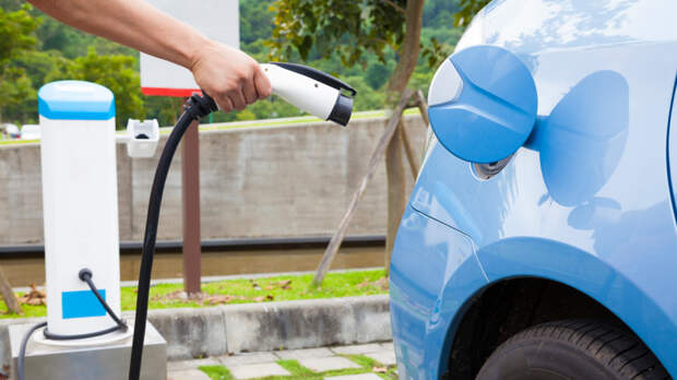 hand holding plug for Charging of an electric car in parking spa