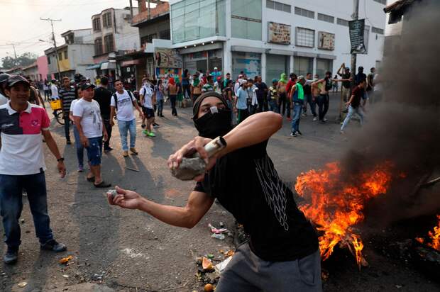 Демонстрант бросает камни во время столкновений с Боливарианской национальной гвардией в Урене, Венесуэла, недалеко от границы с Колумбией, в субботу…