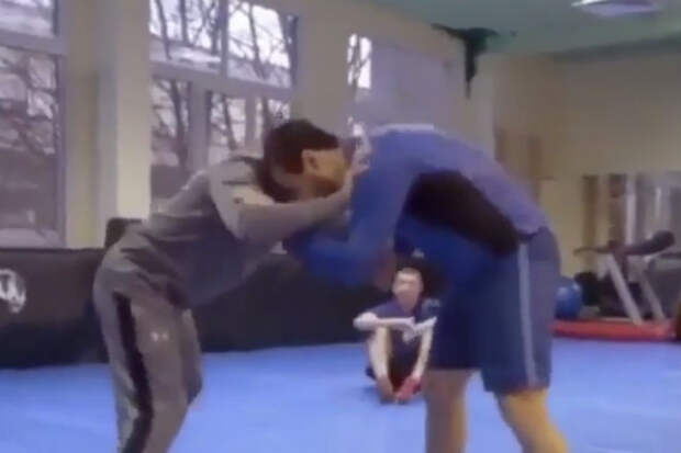 пожилой тренер разговаривает с юным борцом в спортивном зале