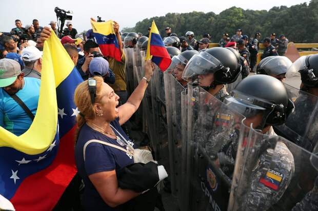 Венесуэльцы стоят перед военнослужащими вооруженных сил Венесуэлы у моста Симона Боливара на границе с Венесуэлой в Кукуте, Колумбия, 23 февраля 2019…