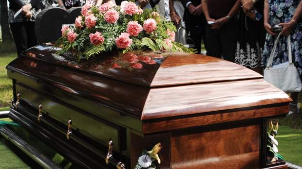 coffin with flowers being lowered into the ground