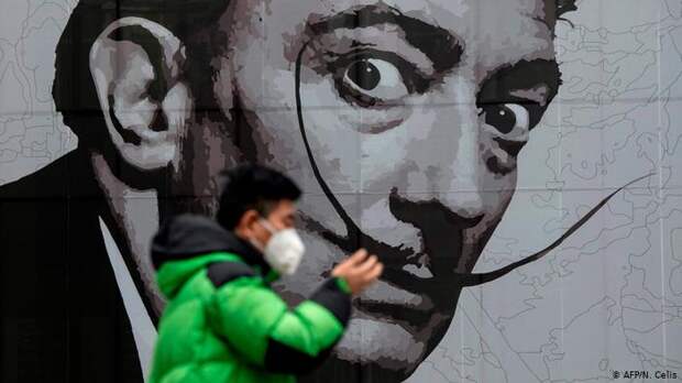 Китаец в маске на фоне граффити с изображением Сальвадора Дали