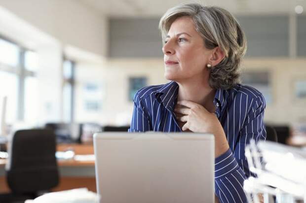 A person sitting in front of a laptop and staring at something in the distance.