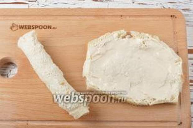 Смазать каждый ломтик хлеба мягким плавленным сыром (100 г) и скрутить рулетиком.