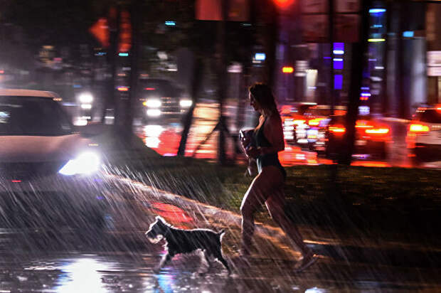 Девушка с собакой во время сильного дождя в Майами-Бич, штат Флорида