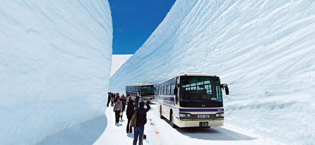 TATEYAMA, JAPAN - MAY 10, 2014: Unidentified tourists walk along snow corridor on Tateyama Kurobe Alpine Route, Japanese Alp in Tateyama, Japan