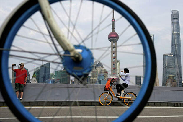 Люди катаются на велосипедах около финансового района Луцзяцзуй в Шанхае 