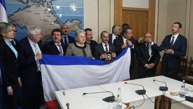 Турецкая делегация во время фотографирования с флагом и гербом Крыма