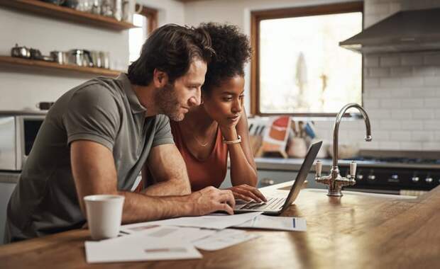 Two people in the kitchen researching on computer. 