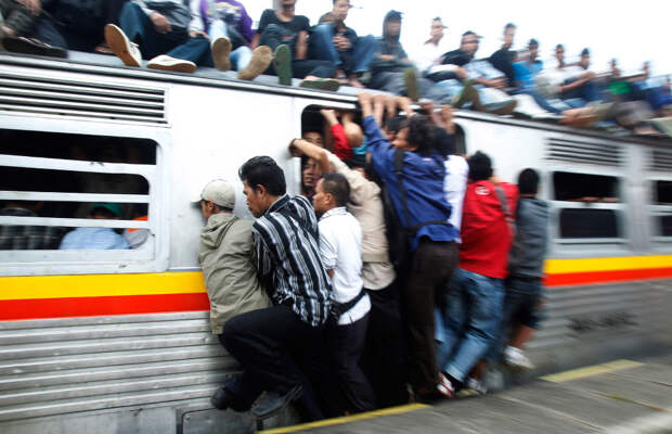 Индонезийские пассажиры уплотняются в поезде в провинции Западная Ява