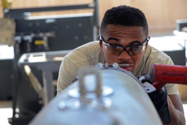 U.S. Air Force Airman 1st Class Tony Chatman, a munitions systems technician currently assigned to the 455th Expeditionary Maintenance Squadron aligns, the front strike of the bomb lugs of a GBU-38. The GBU-38 is the prime bomb utilized with the F-16C Fig